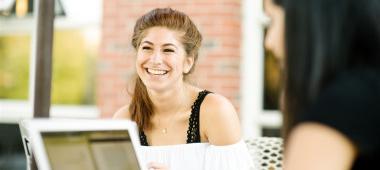 一个坐在户外笔记本电脑前微笑的女人